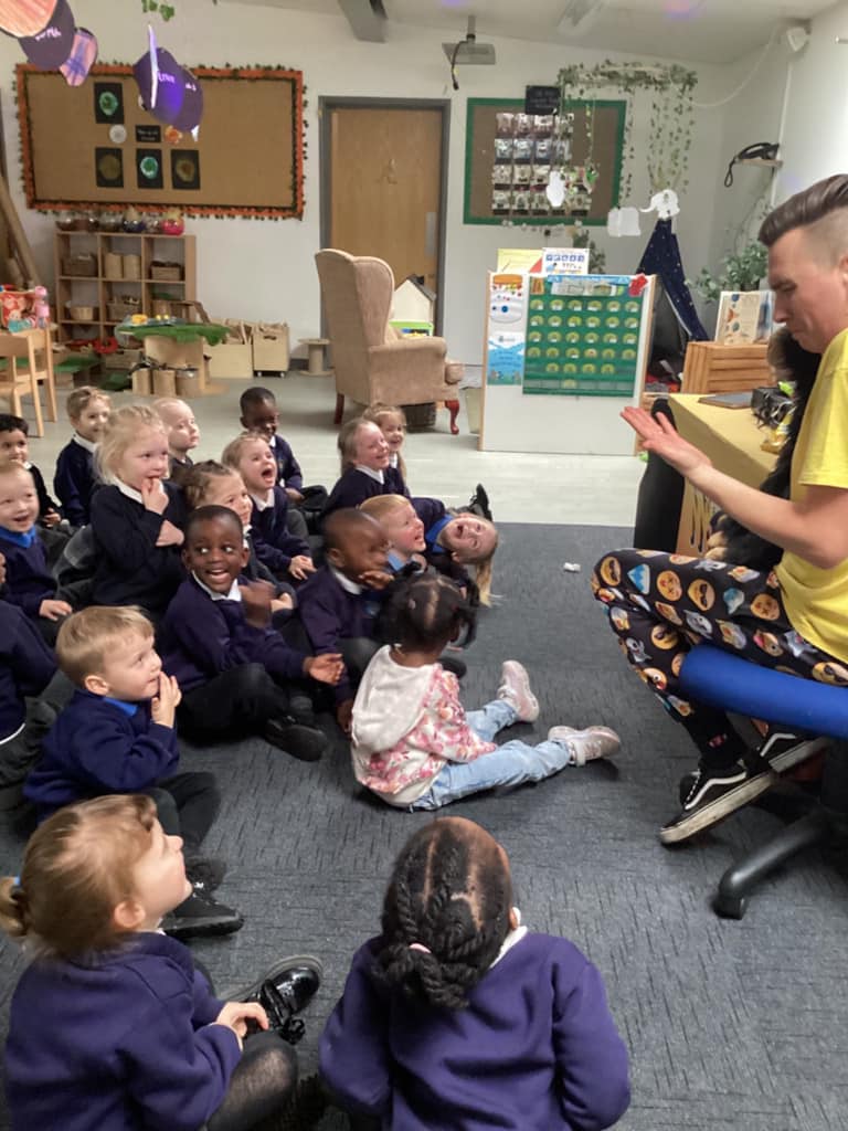 Children sat on the floor watching an entertainer