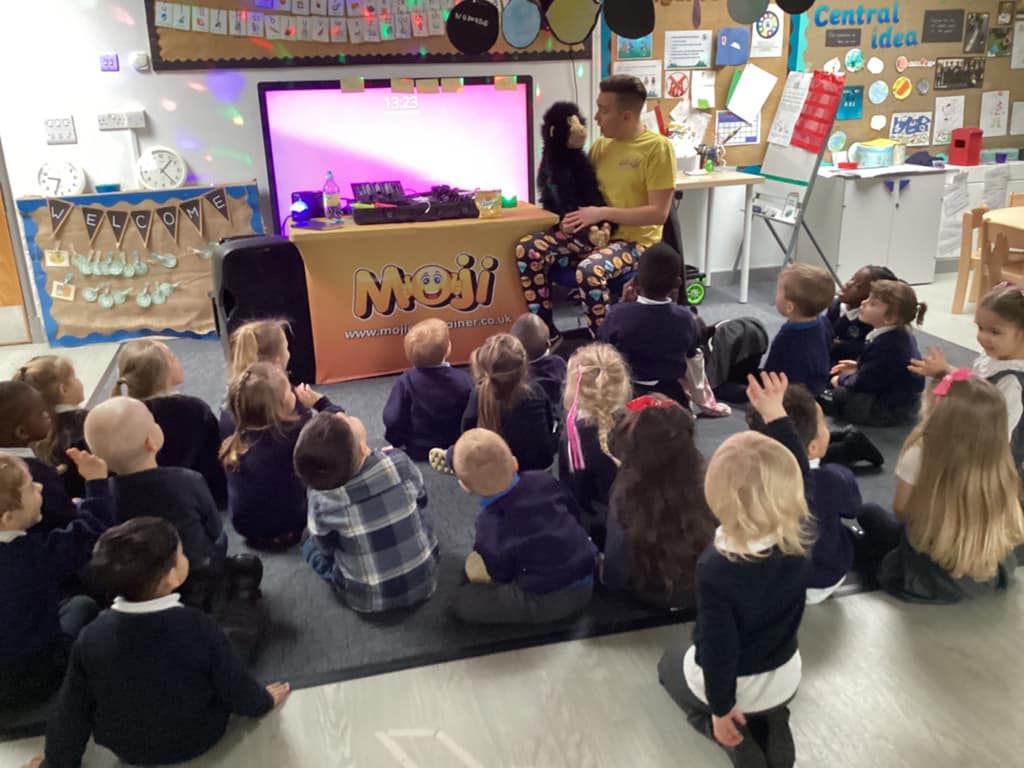 Children sat on the floor watching an entertainer