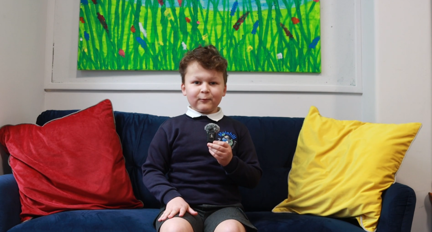 A boy sitting on a sofa with a camera microphone in his hand